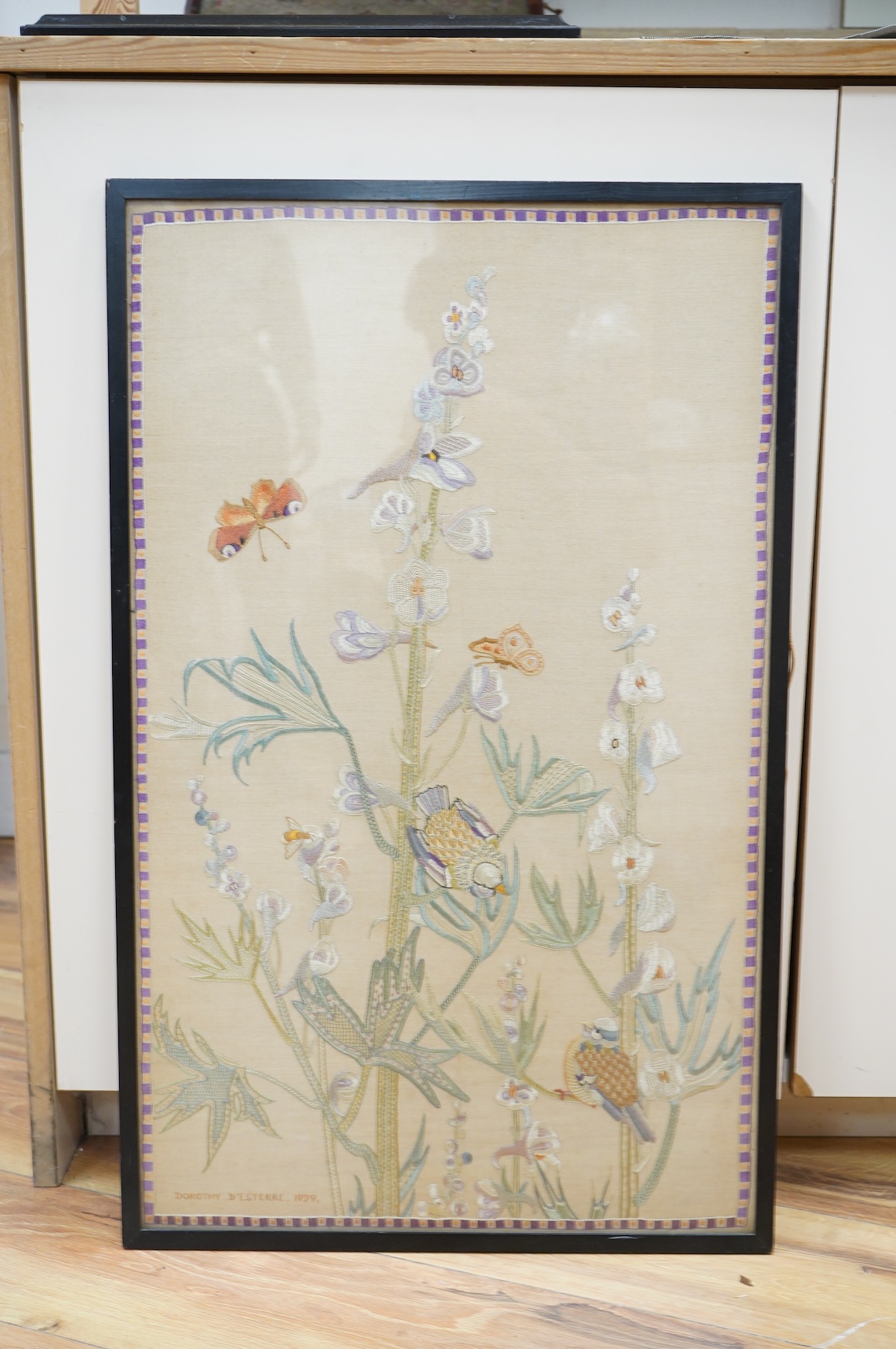 An early 20th century embroidery of birds amongst garden flowers worked in pastel colours, signed to the base Dorothy D'Esterre, dated 1929